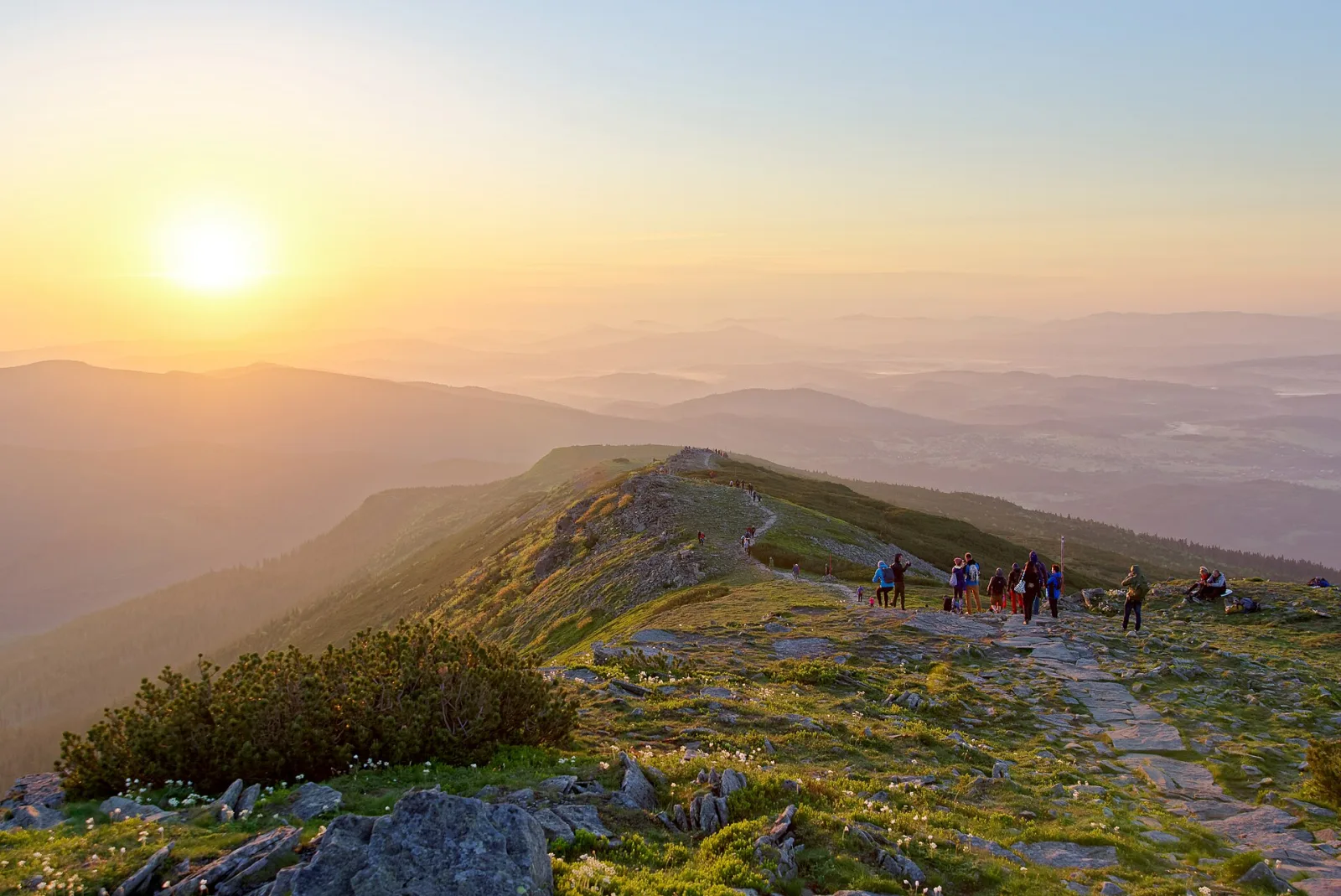 The Babia Gora ridge at sunrise, hikers on the stone trail near the summit