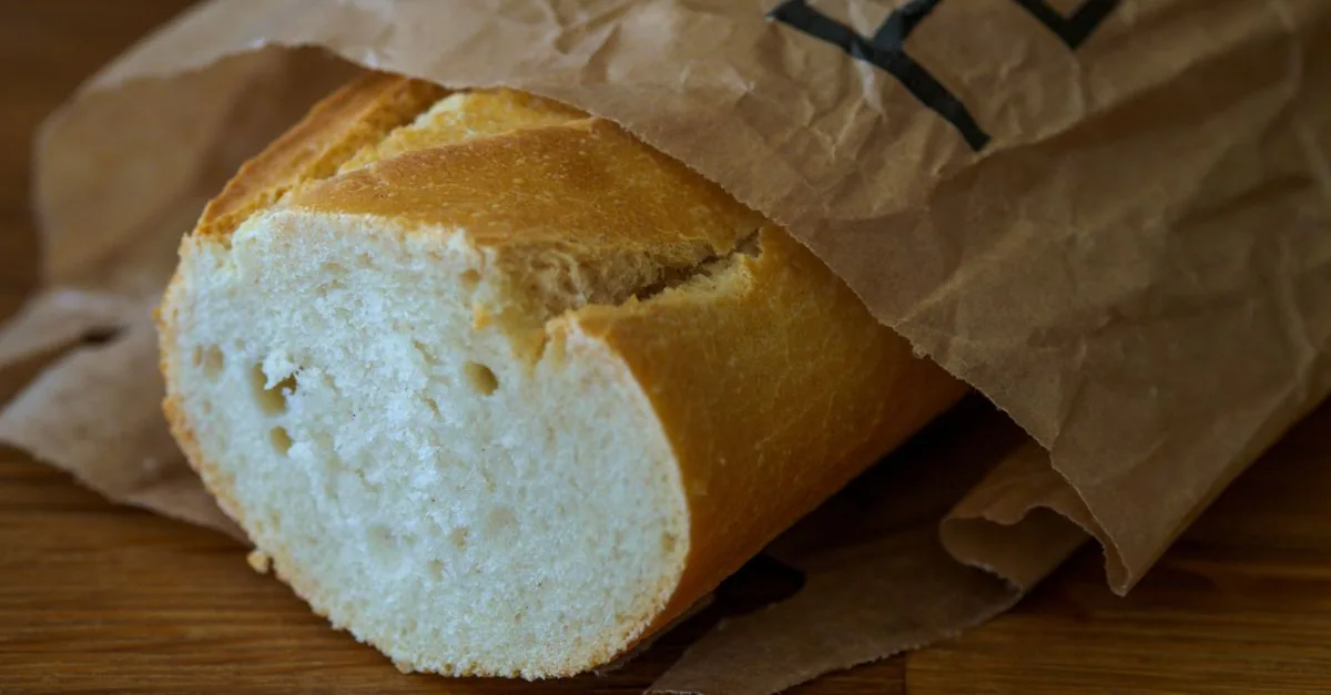 Dog looking at a slice of plain bread on a wooden board