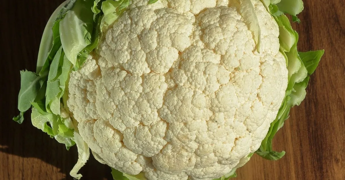 A cauliflower head on a wooden board