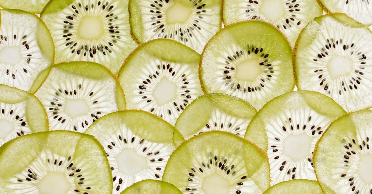 Pies patrzący na plasterki kiwi leżące na drewnianej desce
