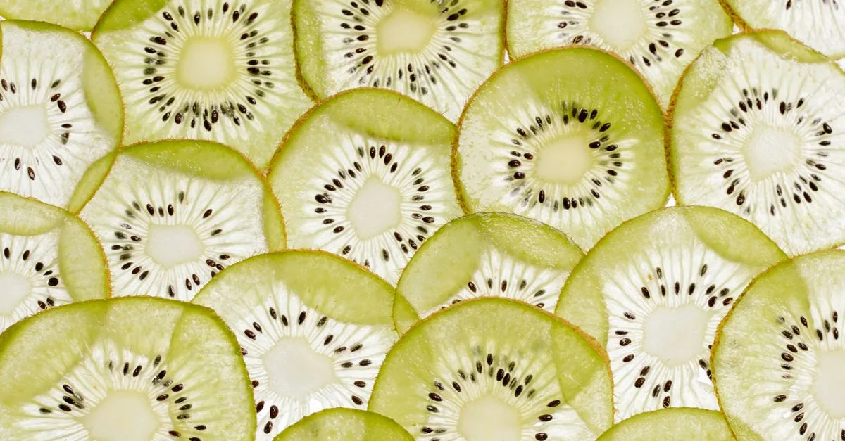 Dog looking at slices of kiwi on a wooden board