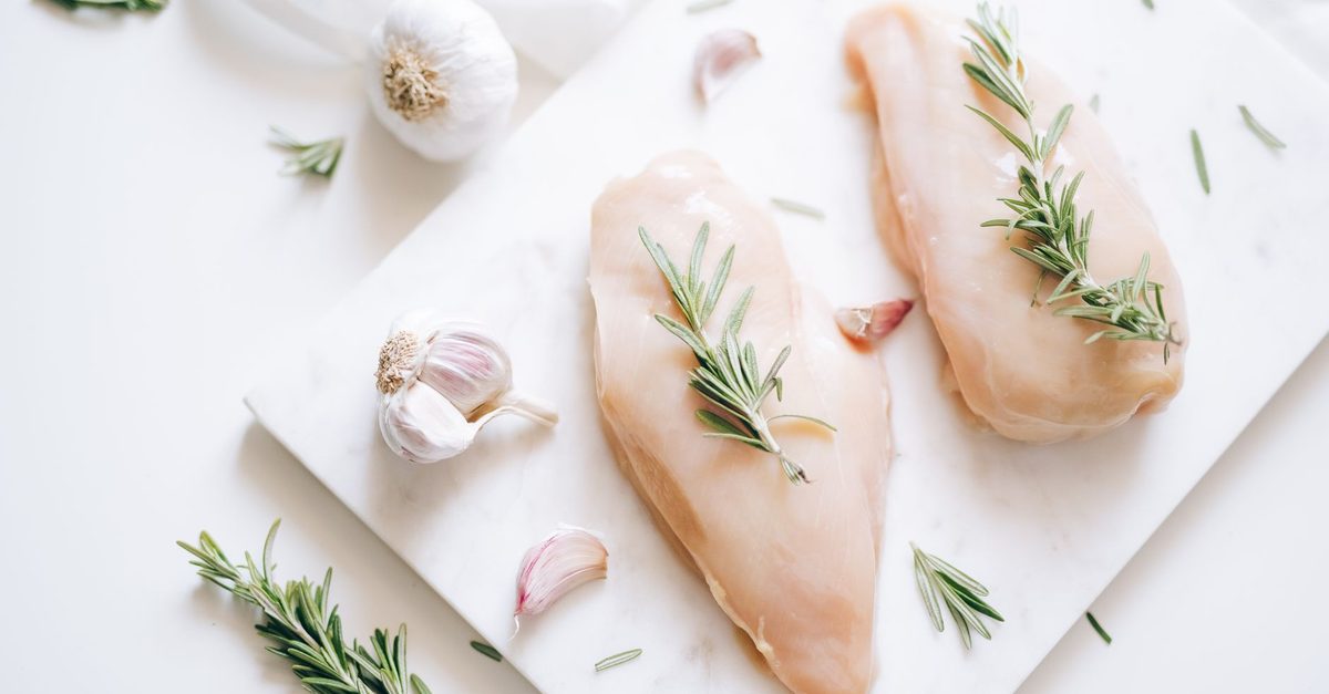 Raw chicken breasts on a board