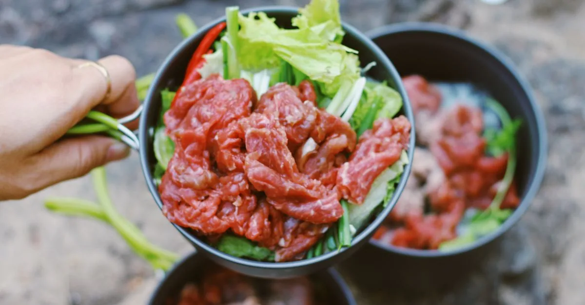 A bowl of raw meat prepared for a dog on a wooden kitchen counter