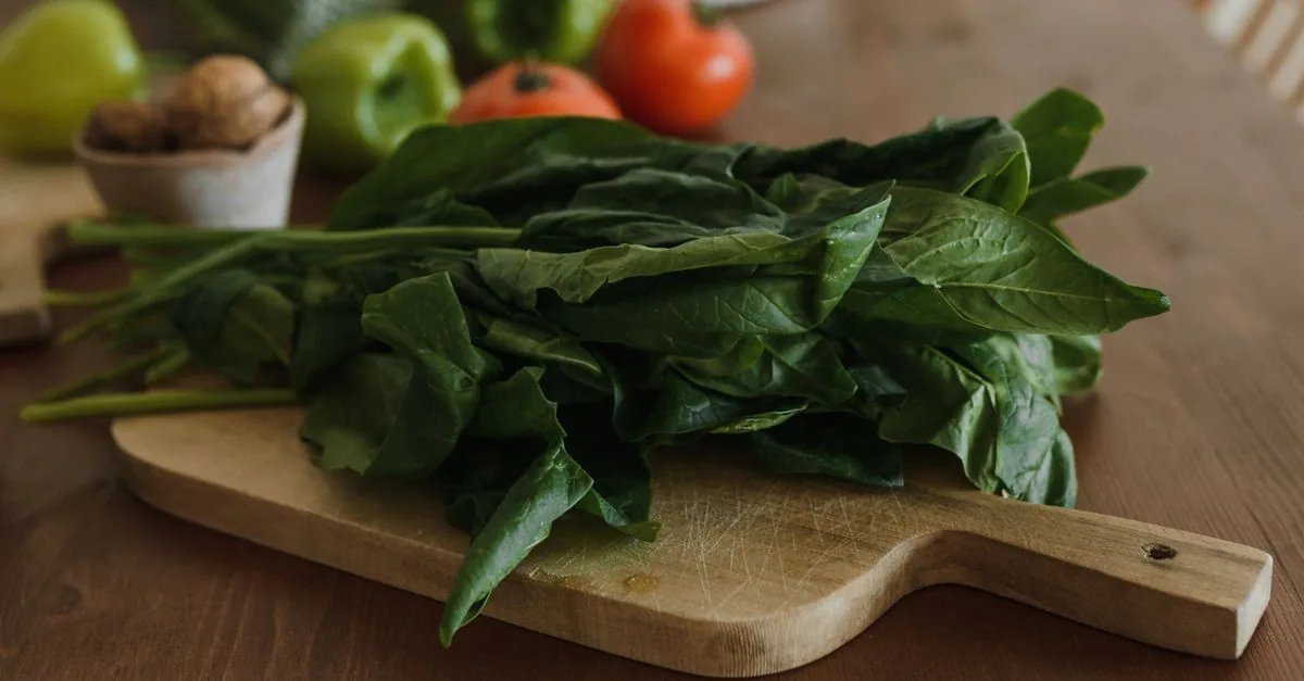 Dog looking at fresh spinach leaves in a bowl