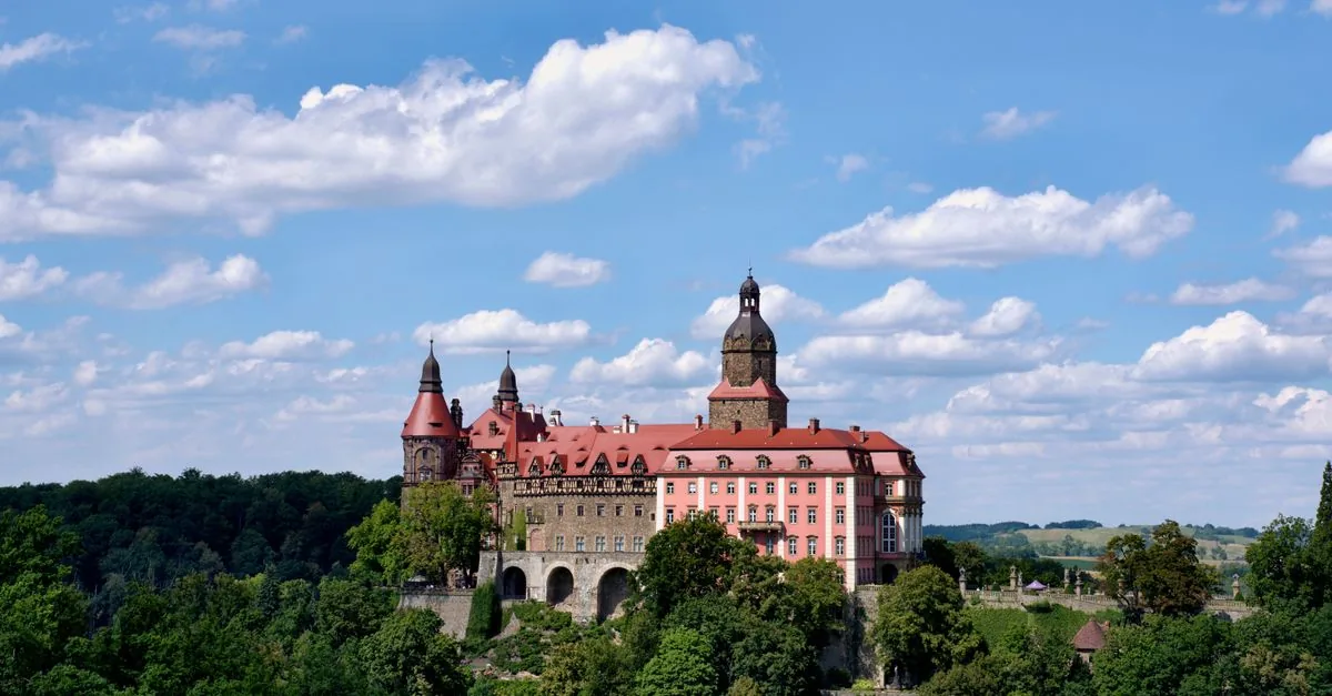 Ksiaz Castle in Walbrzych seen from a distance, surrounded by green hills