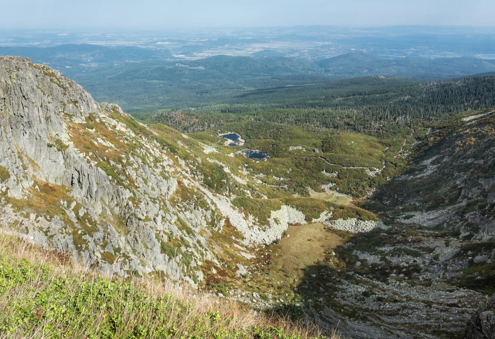Śnieżne Kotły w Karkonoszach, skalne ściany kotła i widok na zalesione doliny