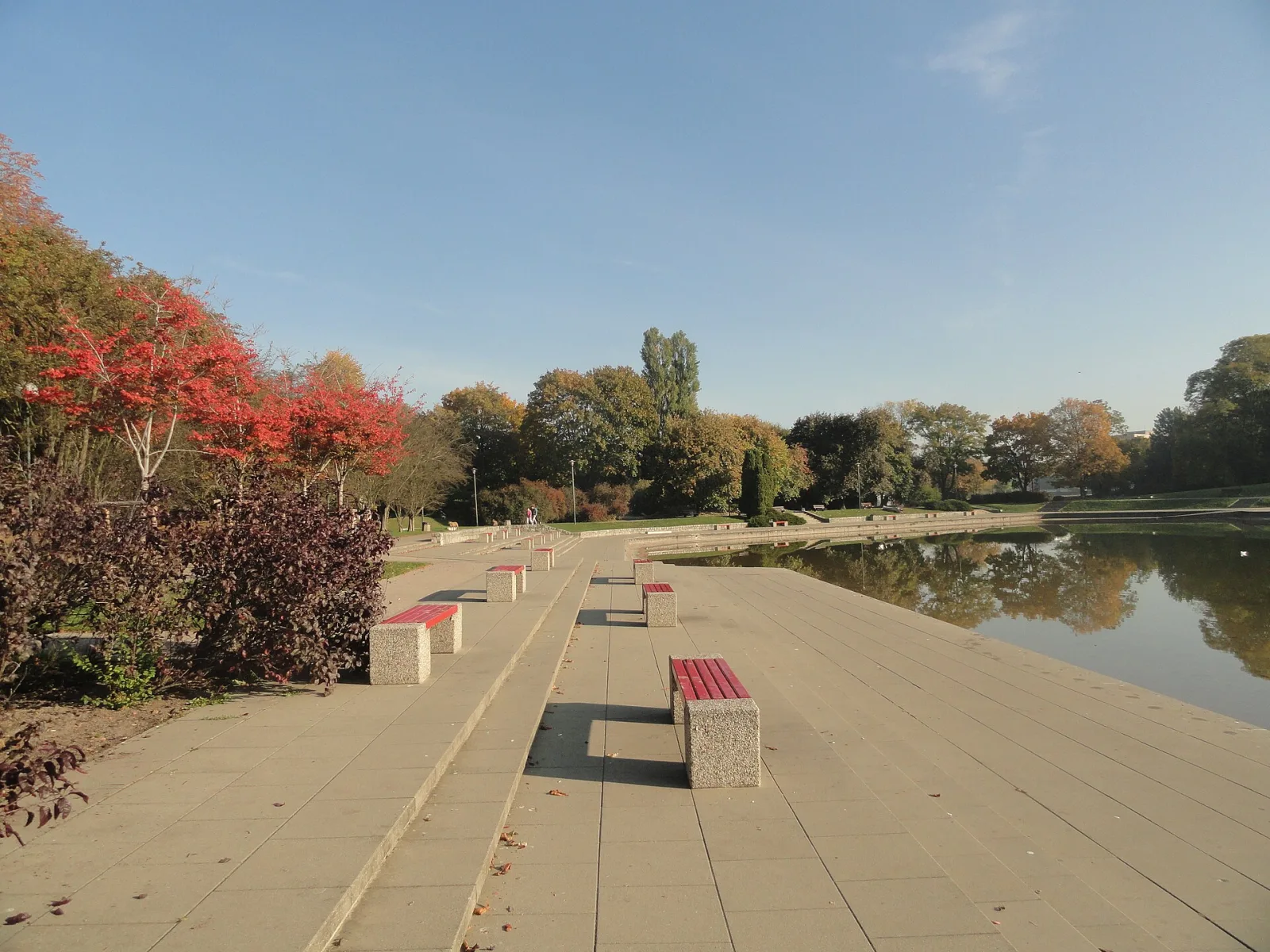 A bench-lined promenade by the pond in Pole Mokotowskie park, Warsaw, in autumn