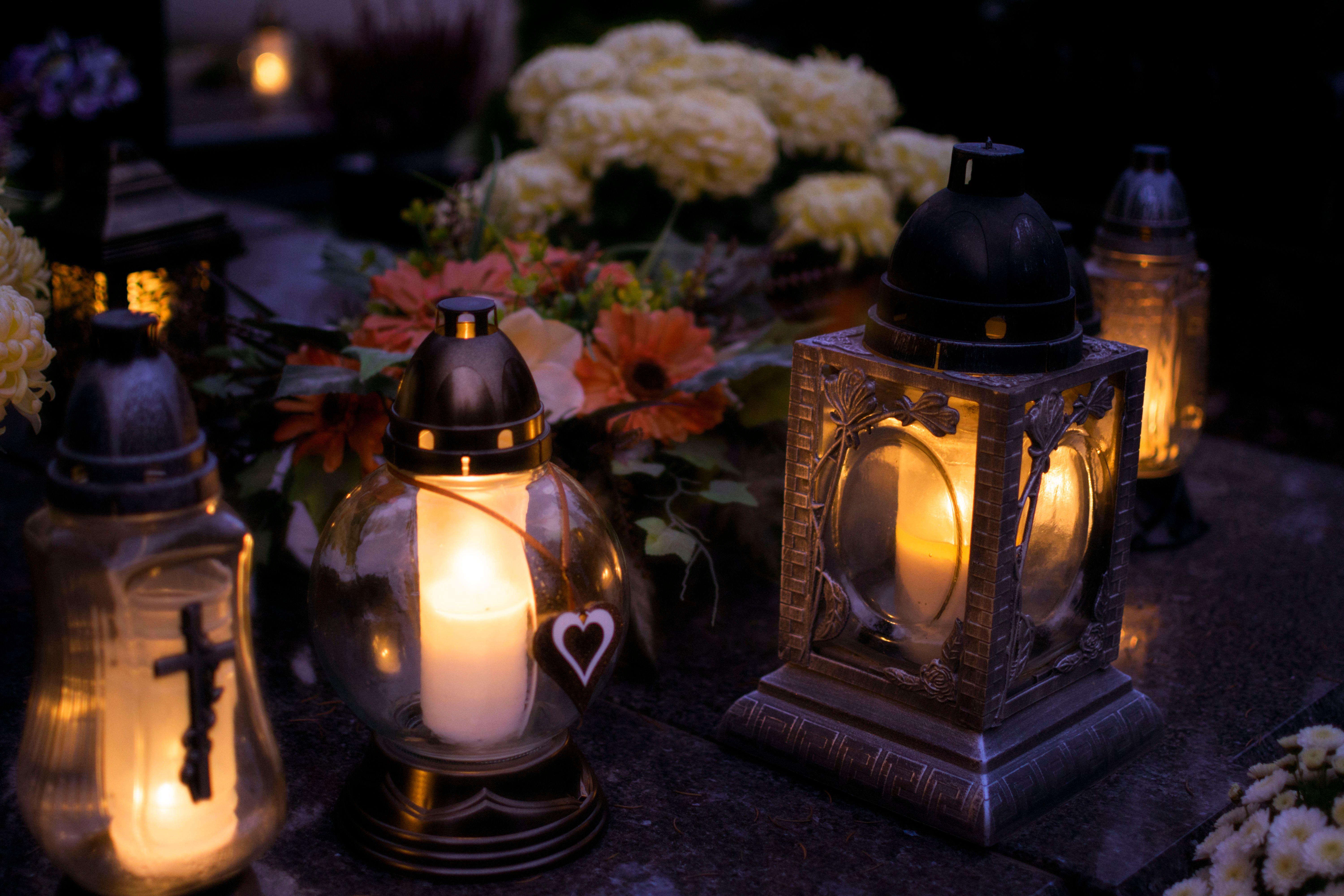 Grave candles burning in a cemetery at dusk, illustrating a guide to All Saints Day