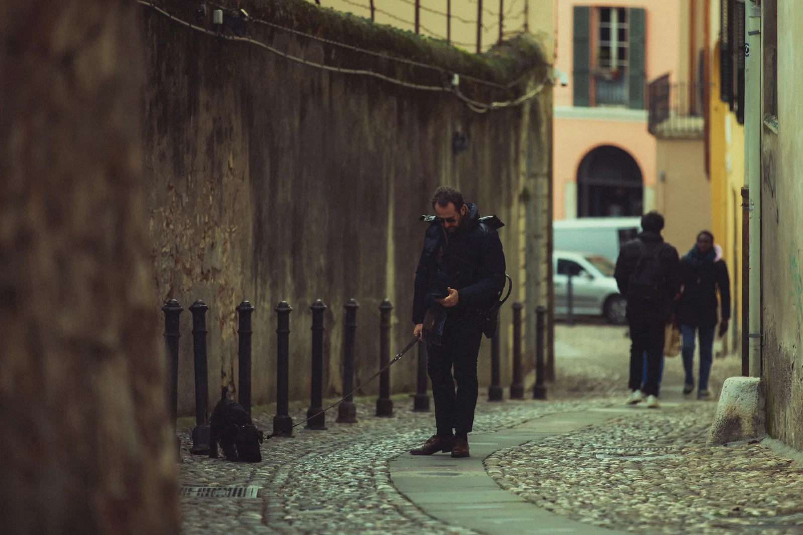 Man walking a dog on an old cobblestone street